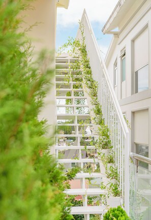 Eine weiße Treppe mit Pflanzen entlang der Brüstung, die zu einem Balkon führt.