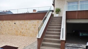 Una escalera que lleva a un garaje, con una planta en maceta en el rellano.