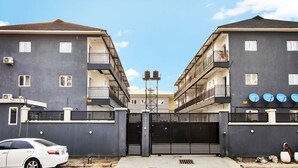 Een omheind wooncomplex met meerdere verdiepingen, balkons en schotels.