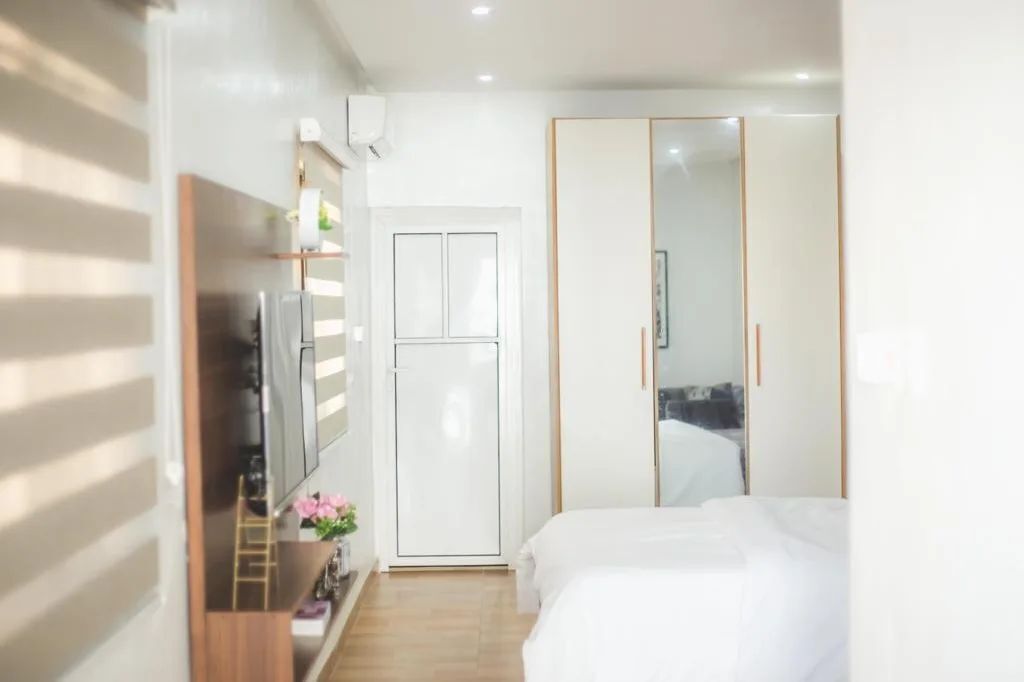 A modern hotel room with a bed, a wardrobe, and a television.