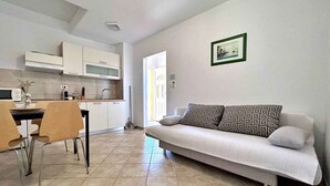 Een moderne woonkamer met een bank en een eethoek met stoelen.