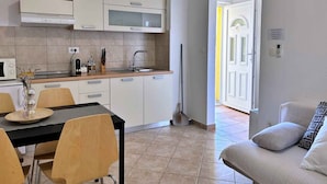 Een moderne keuken met witte kasten, een magnetron en een eethoek met houten stoelen en een tafel.