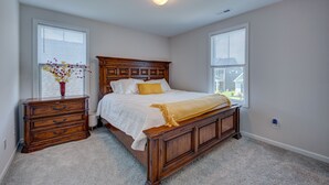Een slaapkamer met een houten bed, een nachtkastje, een kast en een vaas met bloemen.