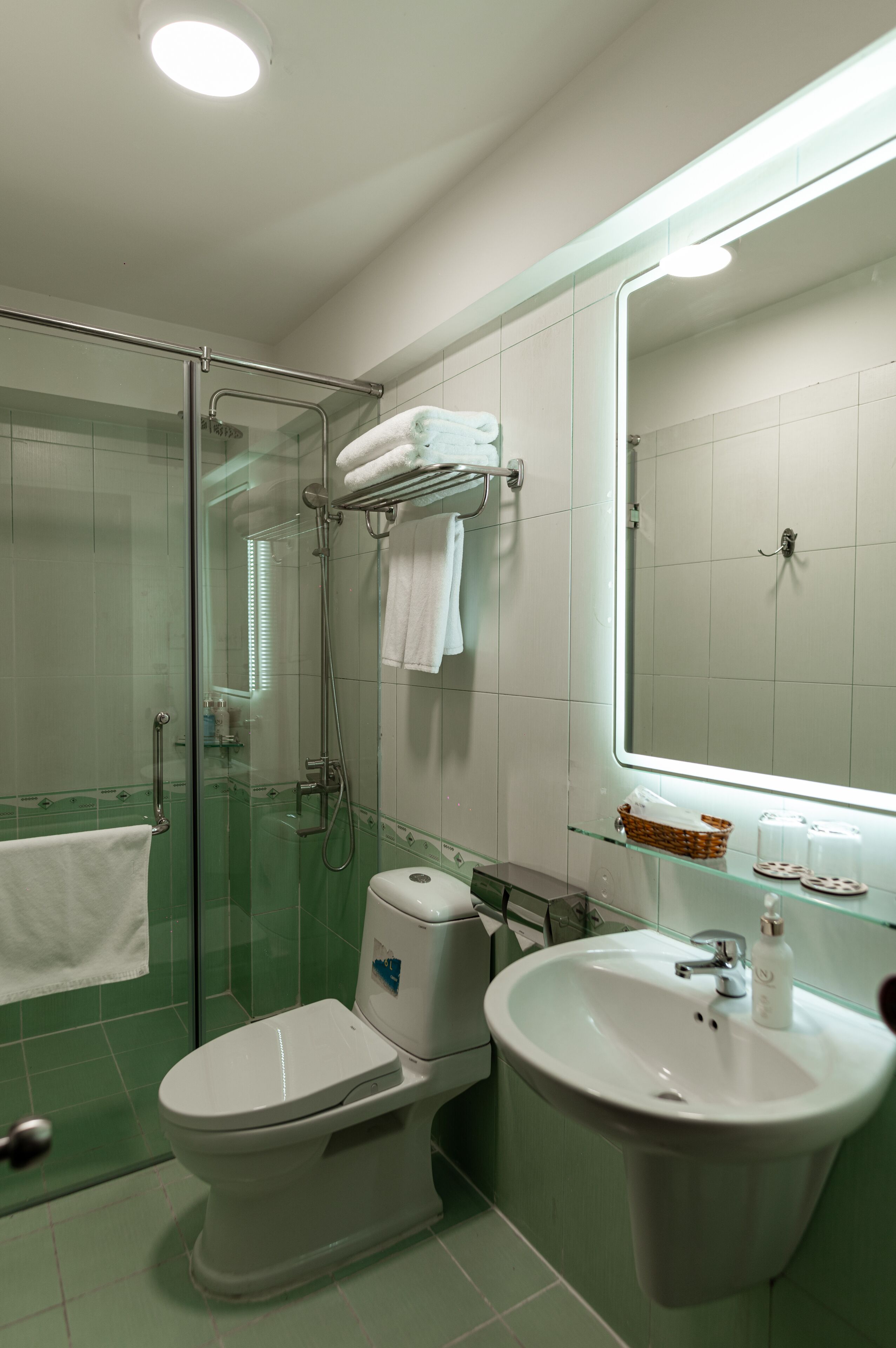 Un baño con cabina de ducha de vidrio, inodoro, lavabo y espejo.