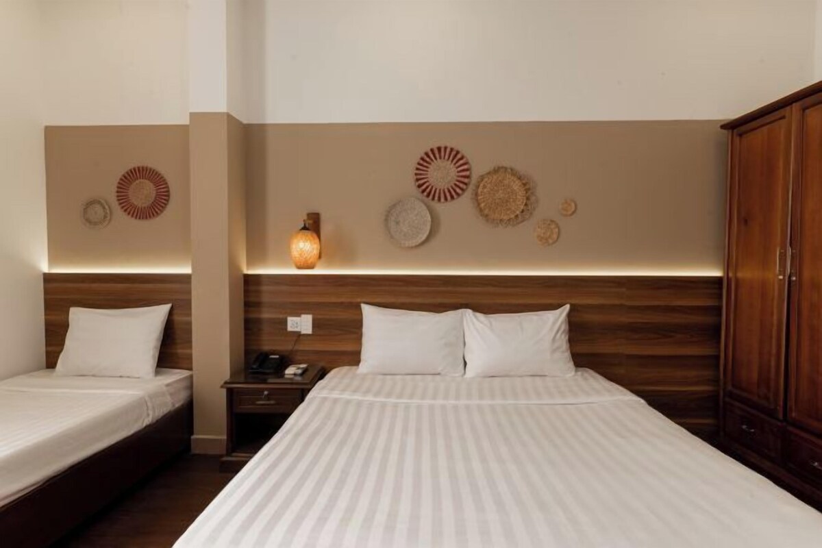 Quarto de hotel com duas camas de solteiro, cabeceira de madeira e arte decorativa nas paredes.