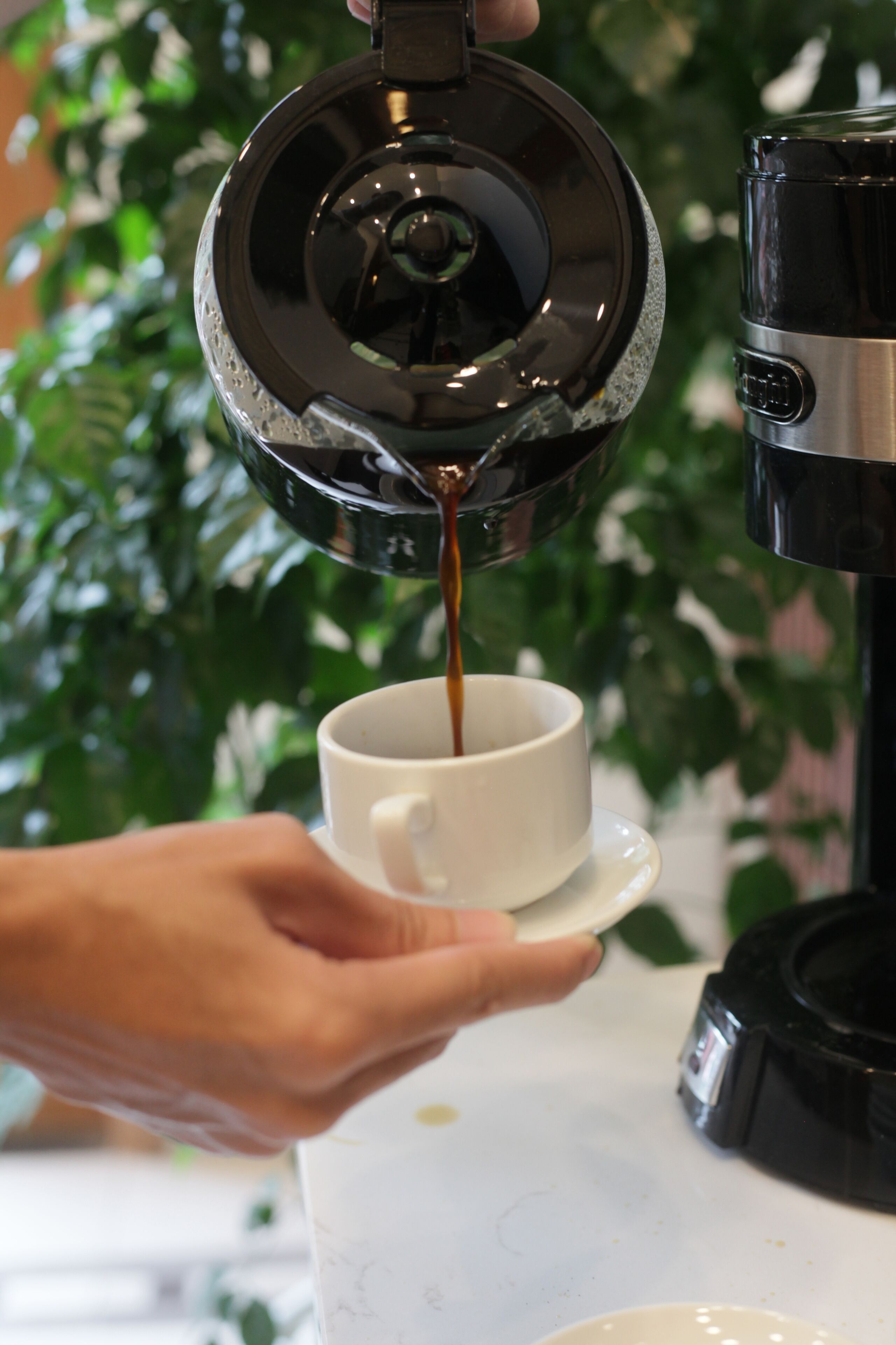 Une main versant du café dans une tasse.