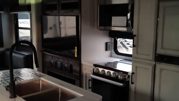 Een moderne keuken met een groot schiereiland, roestvrijstalen apparatuur en een raam dat voor natuurlijk licht zorgt.