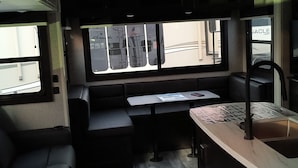Een compact camperinterieur met een kitchenette, zithoek en een raam met uitzicht.