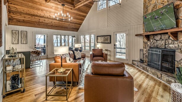 A spacious living room with a fireplace, wooden ceiling, and large windows. - Sunrise and Stardust - Hot Tub | Mountain Views | Screened Porch | (Morganton)