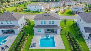 A residential area with modern houses, a central swimming pool, and well-maintained lawns. - Modern Oasis. Enjoy Resort amenities, 10 min to Disney and Attractions.  (Kissimmee)