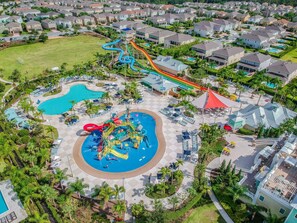 Un parc aquatique doté de nombreux toboggans et de plusieurs piscines, entouré de maisons résidentielles.