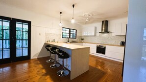 Una cocina moderna con una isla central, taburetes de bar, horno empotrado y un ventanal grande.