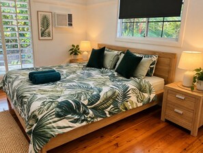 Ein Schlafzimmer mit Bett, Nachttischen, einem Fenster mit Ausblick und einer Wandklimaanlage.
