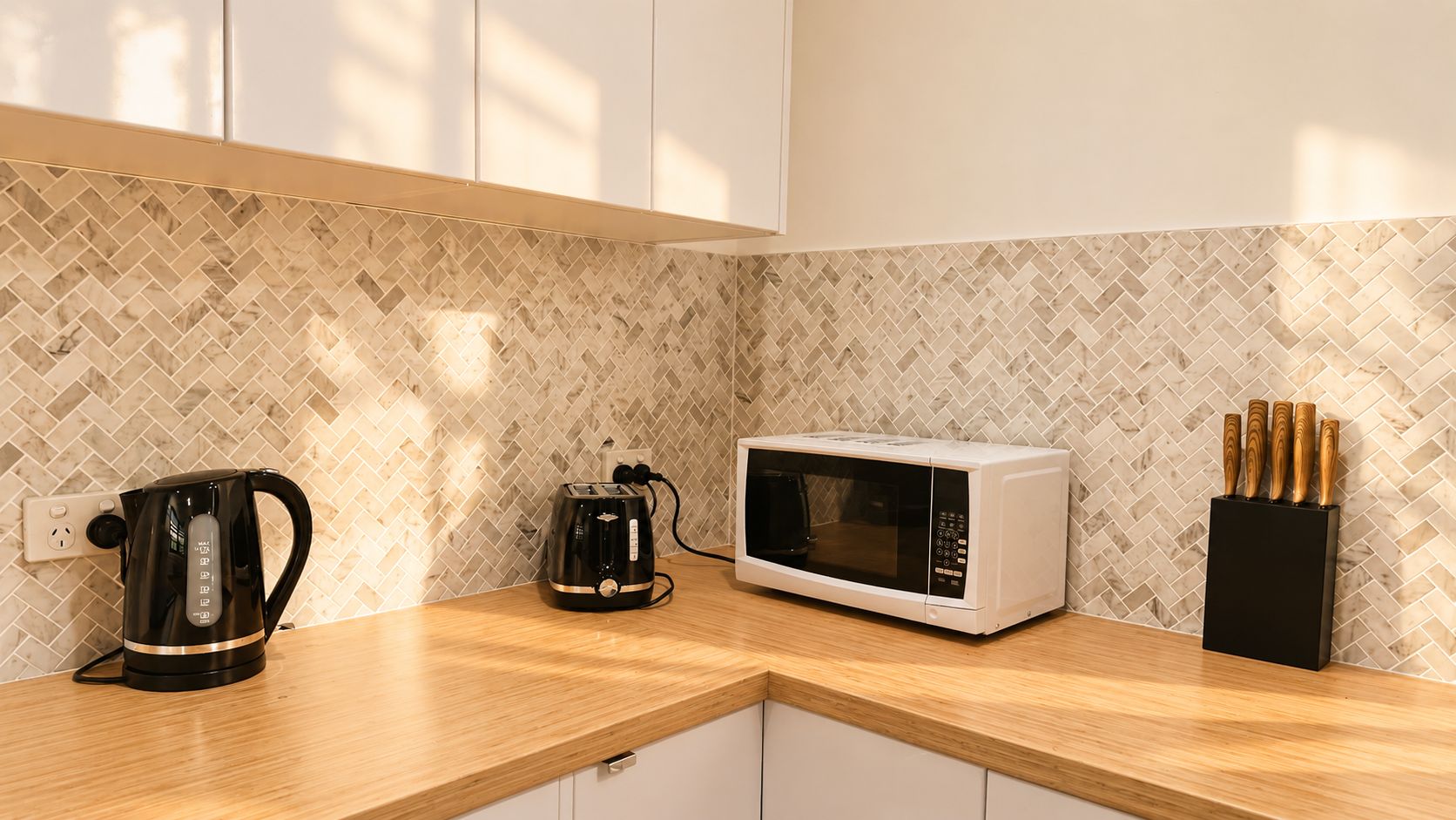 Une cuisine équipée d’un four à micro-ondes, d’une bouilloire et d’un bloc à couteaux, le tout posé sur un plan de travail en bois.