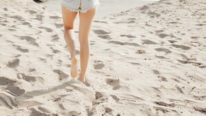 A person walking on a sandy beach with the ocean in the background. - Blvd Sunset. . . Beachfront Condos (Ensenada)