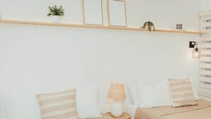 A bedroom with two beds, a bedside table with a lamp, and a shelf with decorative items. - Blvd Sunset. . . Beachfront Condos (Ensenada)