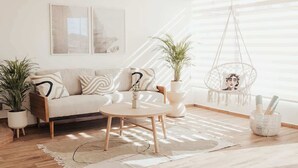 A modern living room with a sofa, coffee table, and potted plants. - Blvd Sunset. . . Beachfront Condos (Ensenada)