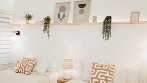 A hotel room with two beds, a bedside table with a lamp, a wall-mounted shelf with decorative items, and a hanging plant. - Blvd Sunset. . . Beachfront Condos (Ensenada)