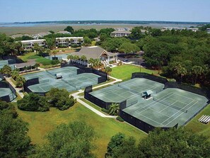 Un complexe de courts de tennis comprenant plusieurs terrains, entouré d’immeubles résidentiels et de verdure.