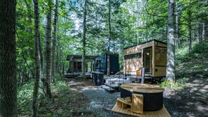 A forest cabin with a wooden deck, a hot tub, and a small outdoor seating area. - Moving Inn Tokachi Kitanomori (Taiki)