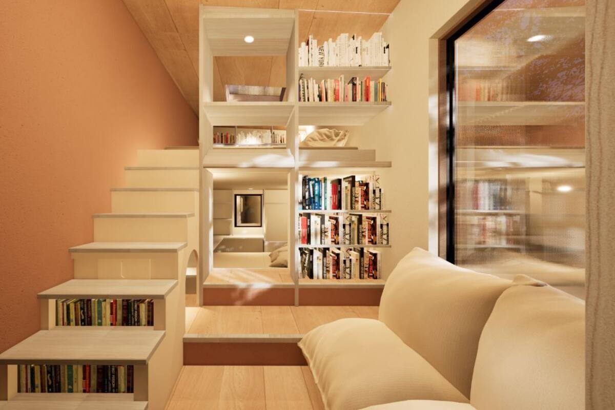 A modern interior with a staircase leading to a loft area, a sofa, and bookshelves filled with books.