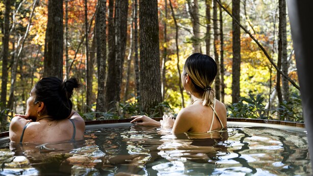 Two people in a hot tub surrounded by trees. - Moving Inn Tokachi Kitanomori (Taiki)