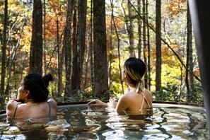 Two people in a hot tub surrounded by trees. - Moving Inn Tokachi Kitanomori (Taiki)