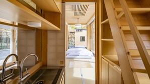 A modern interior with a kitchen area, a bed, and a staircase. - Moving Inn Tokachi Kitanomori (Taiki)