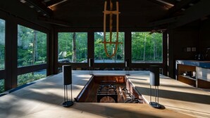 A spacious room with large windows, a central wooden table, and a hanging wooden sculpture. - Moving Inn Tokachi Kitanomori (Taiki)
