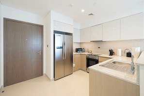 A modern kitchen with a built-in oven, microwave, and stainless steel refrigerator. - 2BR | 2 Pools & Gym | Burj Khalifa | Dubai Mall (Dubai)