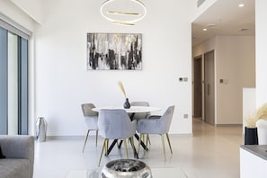 Un área de comedor moderna con una mesa redonda, sillas tapizadas en gris y un cuadro abstracto contemporáneo en la pared.