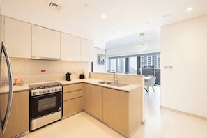 A modern kitchen with a built-in oven, a stainless steel refrigerator, and a large window offering a city view. - 2BR | 2 Pools & Gym | Burj Khalifa | Dubai Mall (Dubai)