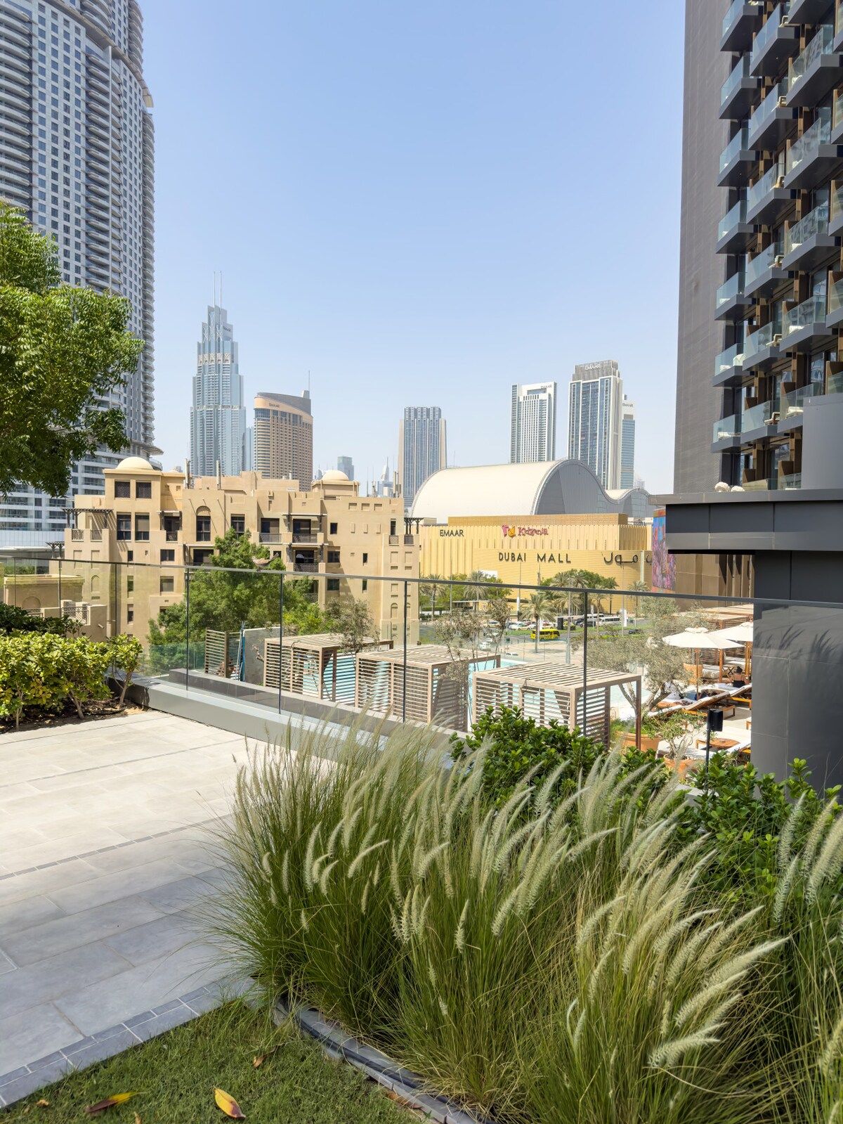 A modern building with a rooftop pool area, surrounded by high-rise buildings and a clear sky.