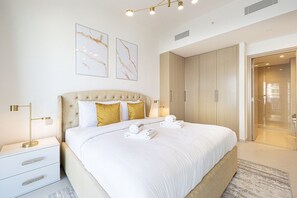 Een moderne hotelkamer met een groot bed, een nachtkastje, een kledingkast en een badkamer die door een open deur zichtbaar is.