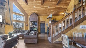 A spacious living area with a wooden staircase, a fireplace, and a view of the outdoors. - Lakefront Gem w/ Gorgeous Views, Boat Slip, Air Hockey & Close to Silver Dollar City (Branson)