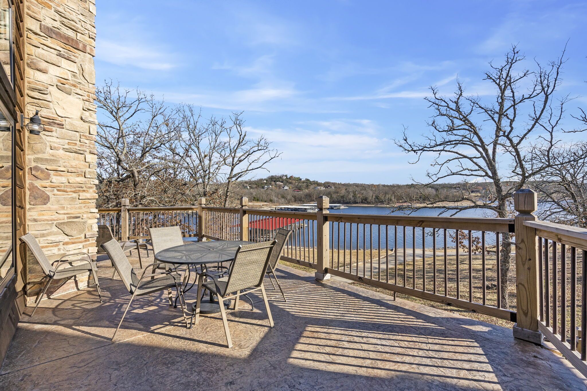 Un bâtiment en pierre doté d’une terrasse aménagée avec du mobilier d’extérieur et offrant une vue sur un lac.