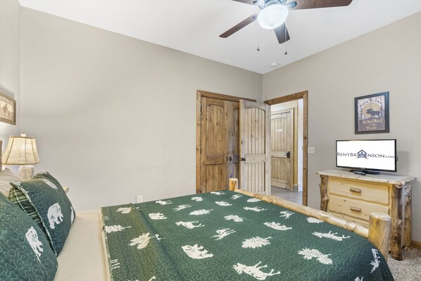 A bedroom with a bed, a wooden nightstand, a television, and a ceiling fan. - Lakefront Gem w/ Gorgeous Views, Boat Slip, Air Hockey & Close to Silver Dollar City (Branson)
