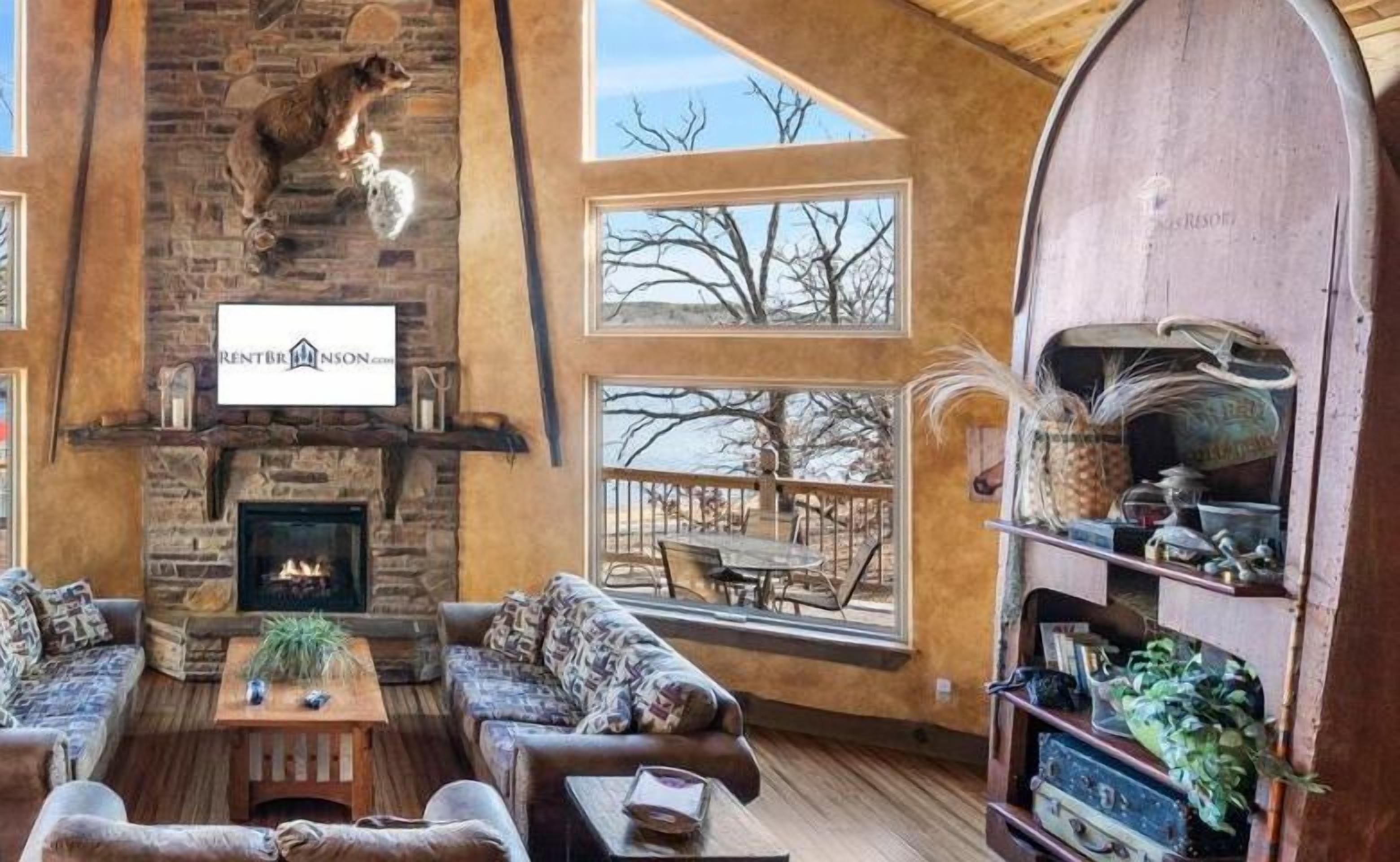 A cozy living room with a fireplace, comfortable seating, and a view of the outdoors.