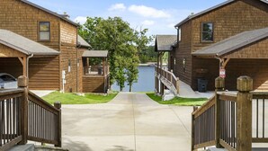 A wooden cabin-style hotel with a lake view, a covered deck, and a concrete driveway. - Lakefront Gem w/ Gorgeous Views, Boat Slip, Air Hockey & Close to Silver Dollar City (Branson)