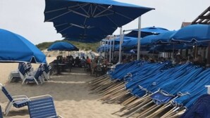 Ein Strand mit blauen Sonnenschirmen und Liegestühlen.