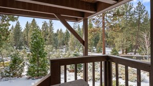 A wooden deck with a view of a snowy forest.