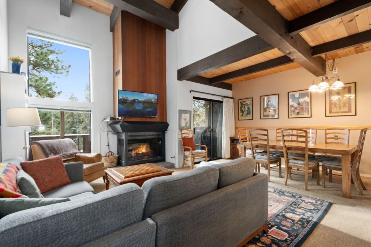 A cozy living room with a fireplace, comfortable seating, a dining area, and artwork on the walls.