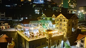 Un hotel con un atrio de cristal, zona de estar al aire libre y terraza en la azotea.