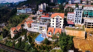 Un hotel con piscina, rodeado de vegetación y varios edificios.