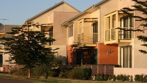 A modern residential building with a flat roof, large windows, and a balcony with a metal railing. - Newcastle Interchange Apartments (Wickham)