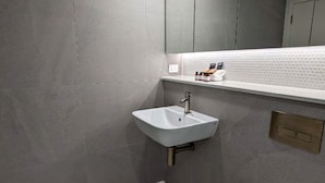 A modern bathroom with a white sink, toilet, and shower area. - Newcastle Interchange Apartments (Wickham)