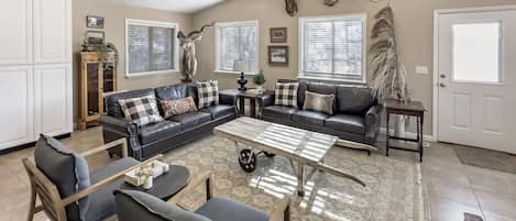 A living room with a sectional sofa, a coffee table, and a chandelier.