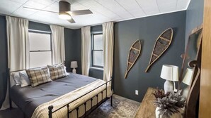A bedroom with a bed, curtains, a ceiling fan, a window, and wall decorations. - Mountain Meadow Retreat near Park City (Peoa)