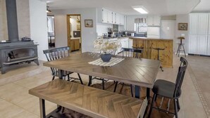 A spacious dining area with a large wooden table, chairs, and a central island with bar stools. - Mountain Meadow Retreat near Park City (Peoa)