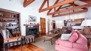 A spacious living room with a fireplace, wooden beams, a sofa, a coffee table, and a bookshelf. - JHRL - Pieper Garden Home 30 night rental (Wilson)